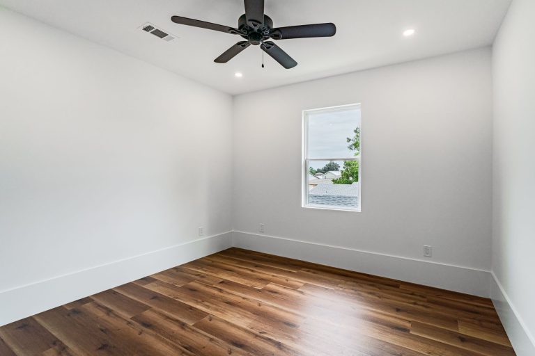 Wide-plank hardwood flooring in an empty Missouri room with white walls and baseboards
