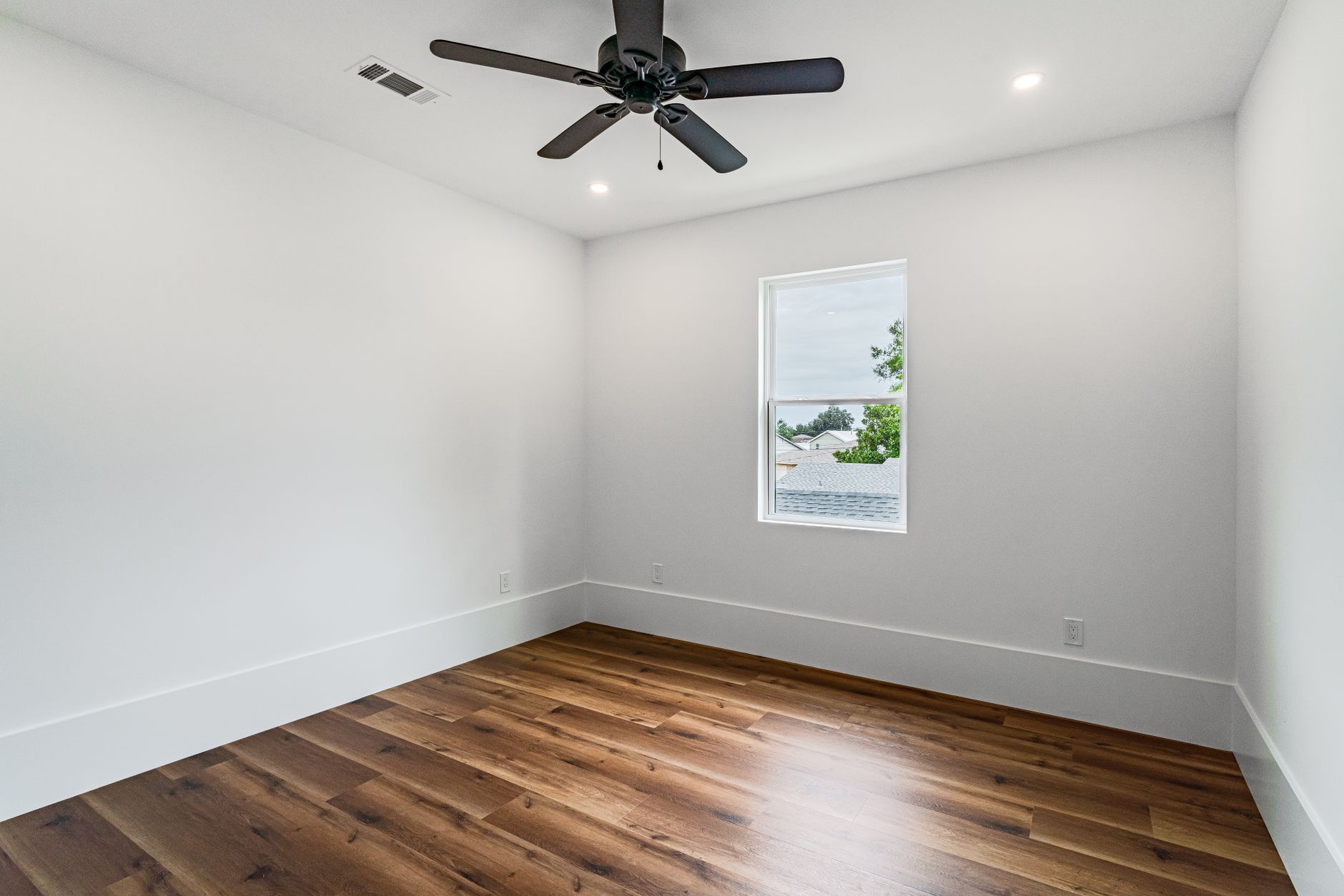 Wide-plank hardwood flooring in an empty Missouri room with white walls and baseboards