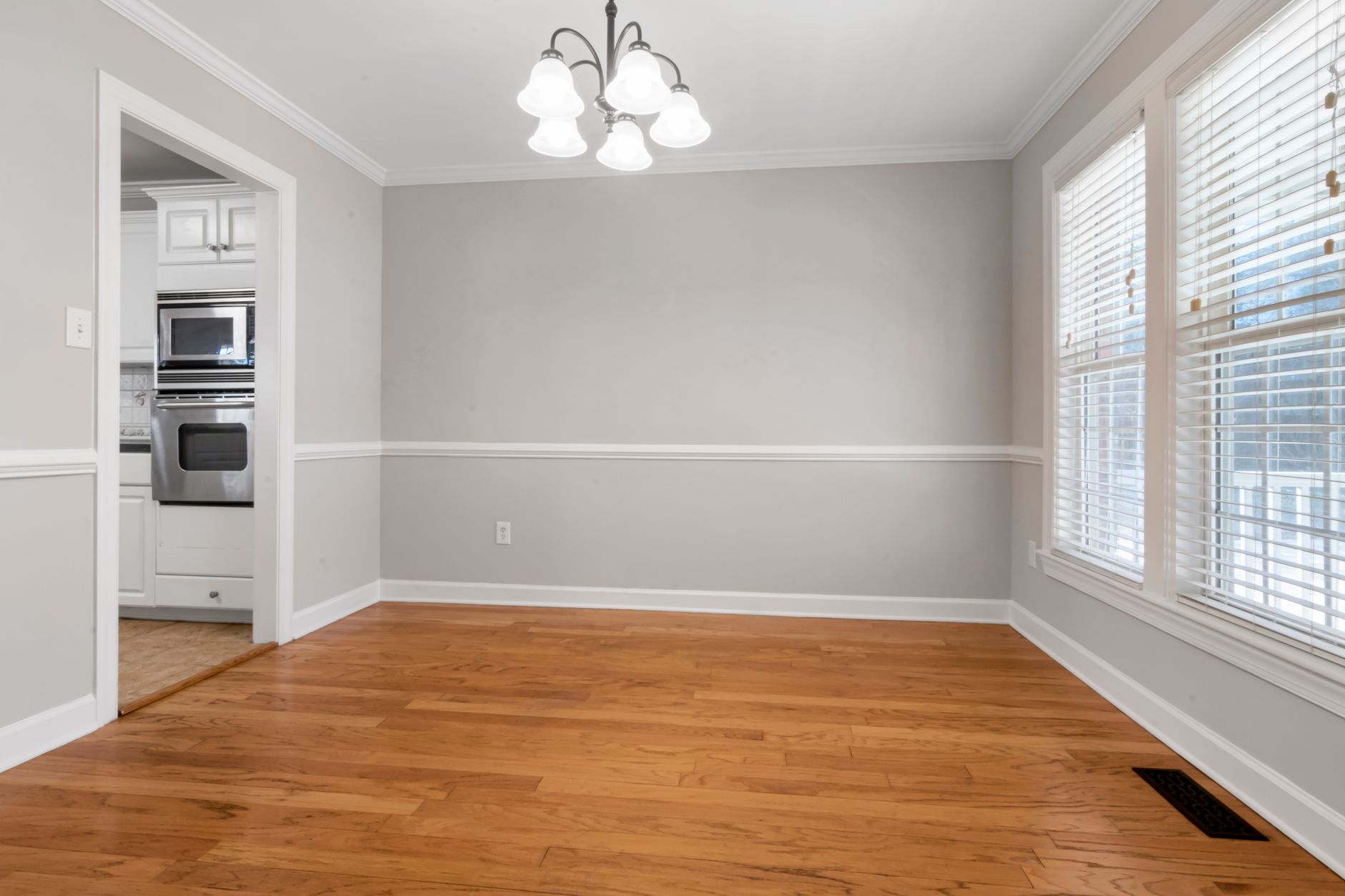 Golden refinished oak flooring in an empty Missouri room with white walls and trim
