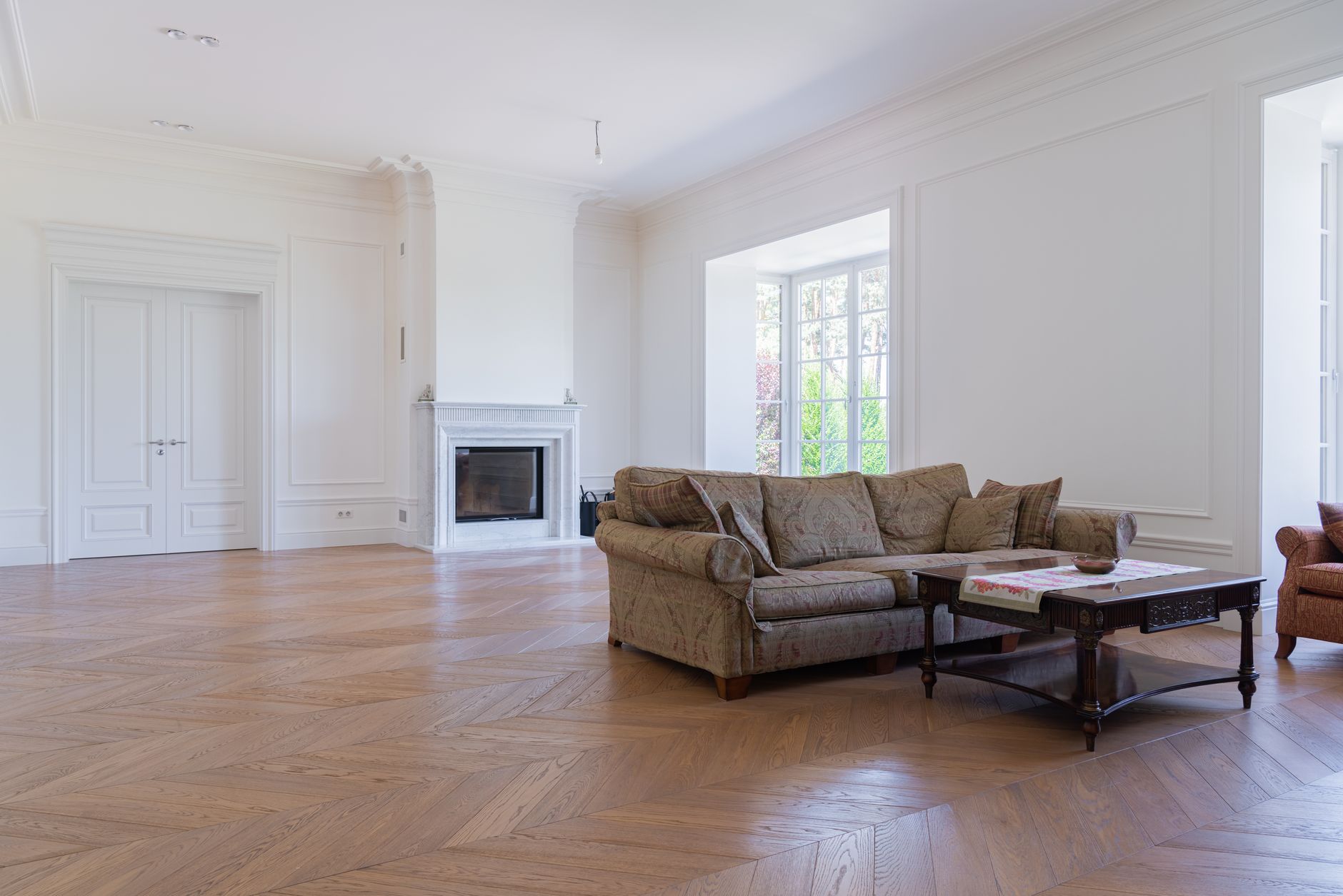 Herringbone hardwood flooring in a Missouri living room with a fireplace and tall windows