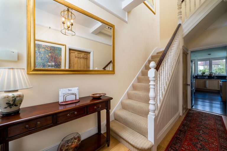 Carpeted stair treads with white balusters in a Missouri entry hall, opening onto a hardwood floor