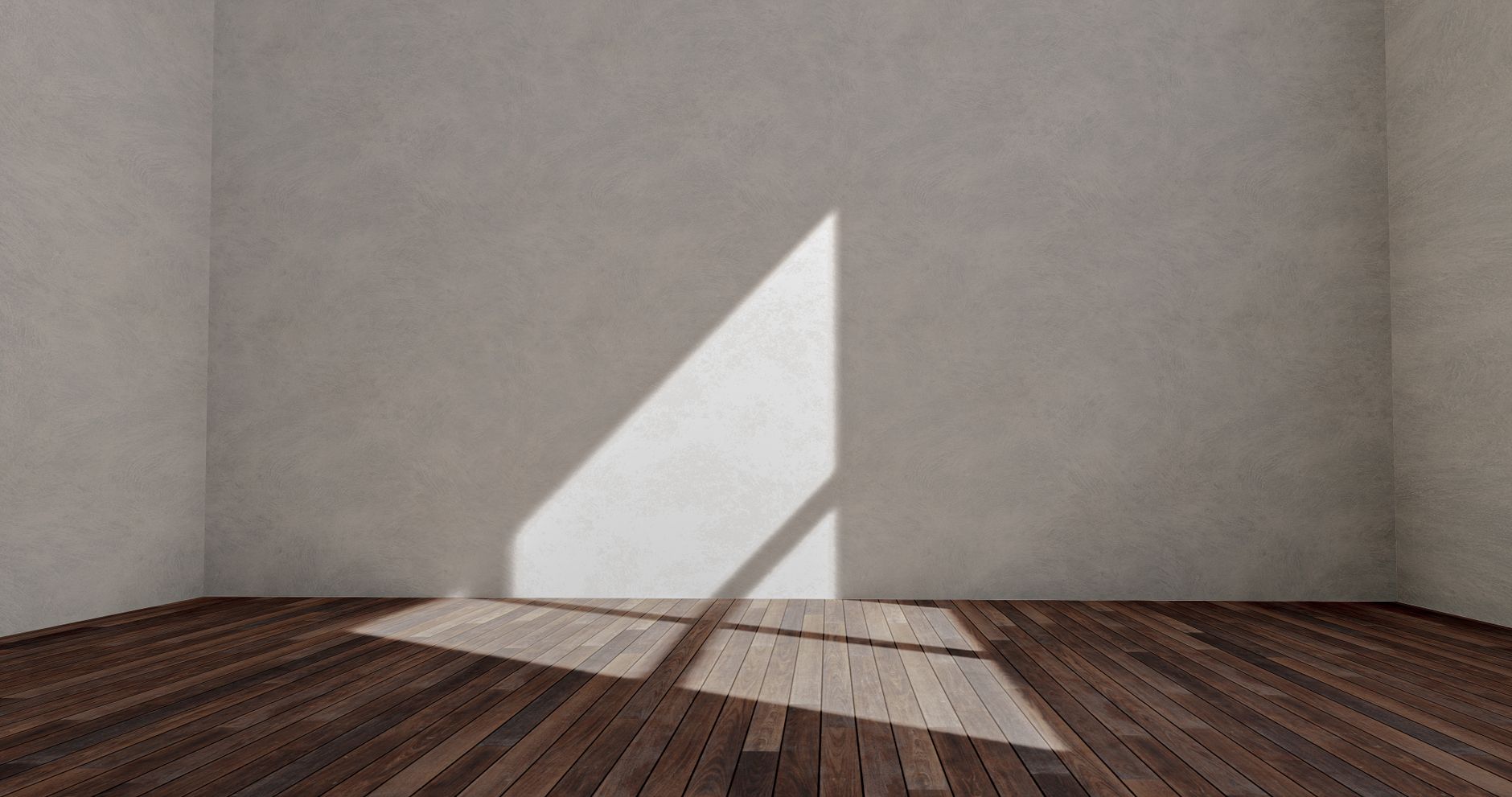 Sunlit empty room with wooden flooring and a shadowed wall, creating a minimalist look