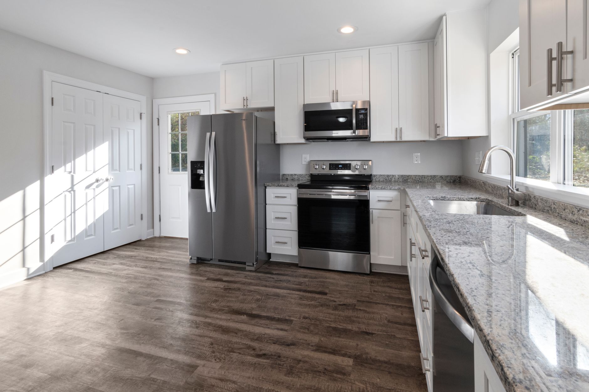 Wood-look plank flooring in a modern Missouri kitchen with stainless appliances and granite counters