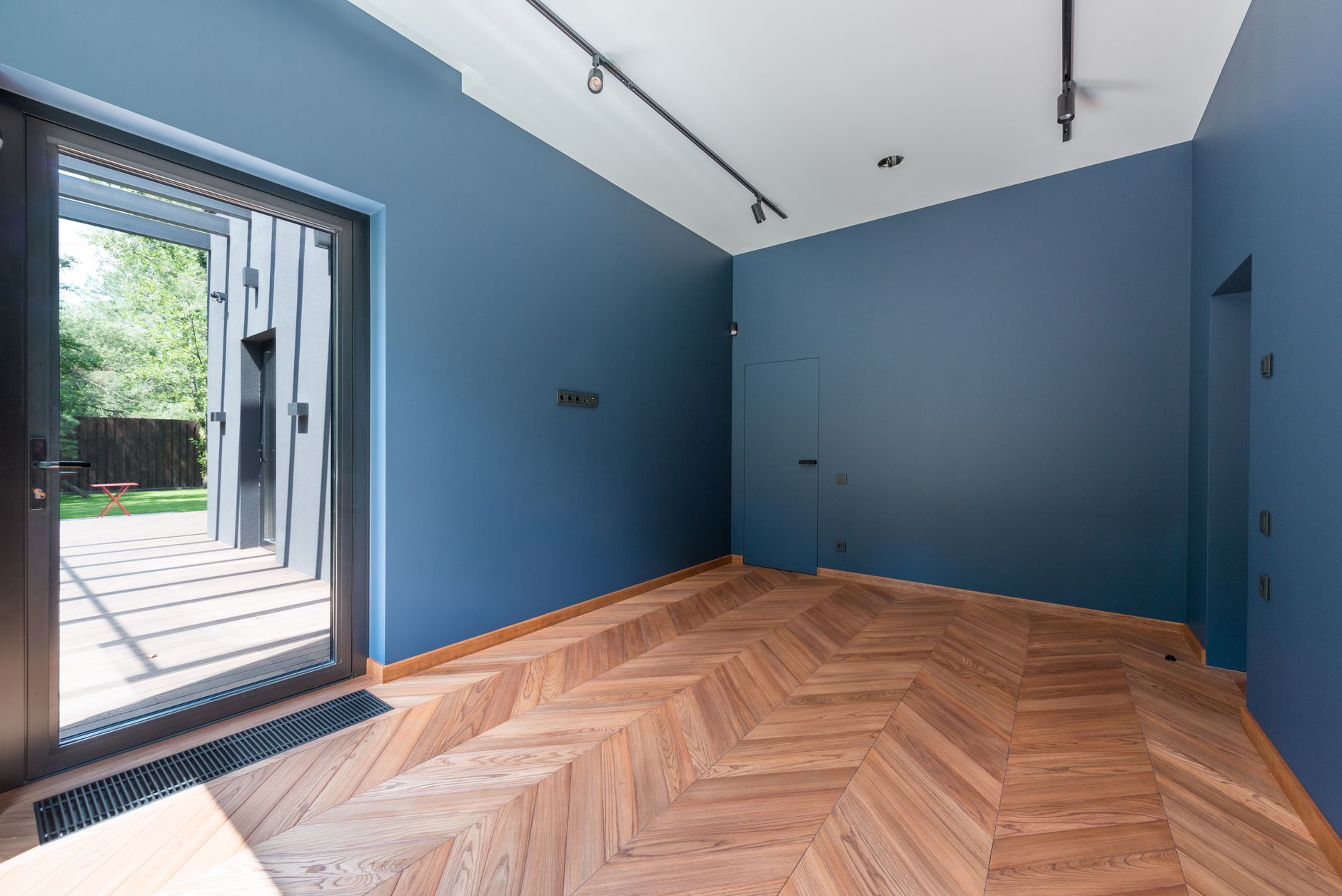 Contemporary interior room with blue walls, wooden flooring, and large glass door