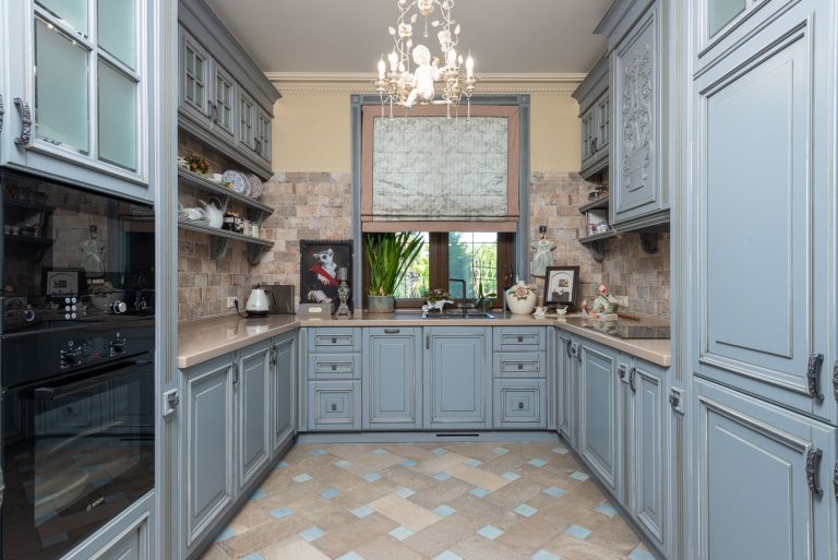 Discover an elegant vintage-style kitchen with classic cabinets and ornate chandelier