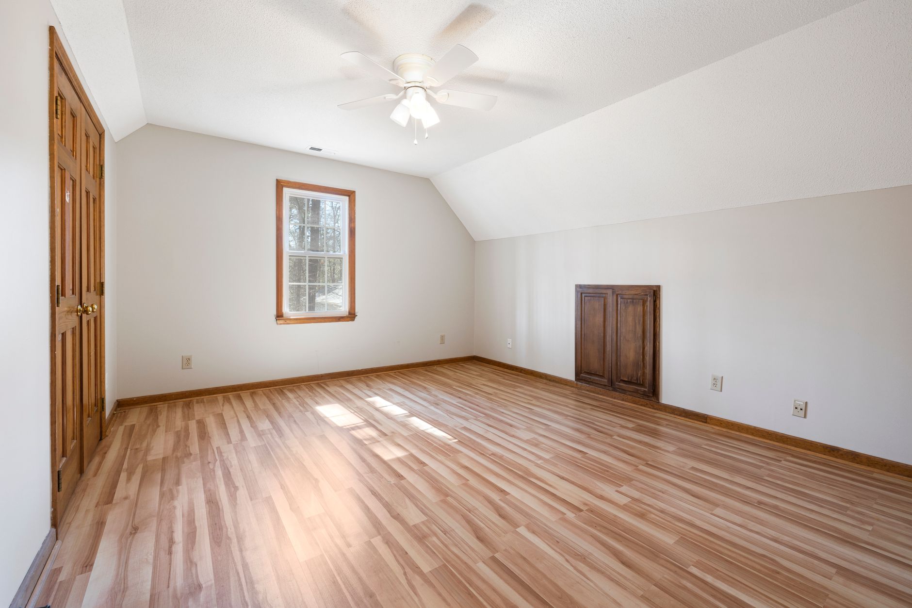 Bright empty room with hardwood floor and ceiling fan